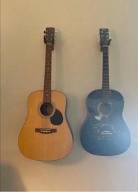 two acoustic guitars hanging on a wall