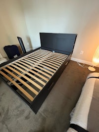 a black bed frame in a room with a mattress on it