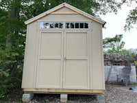 a tan shed sitting in a yard