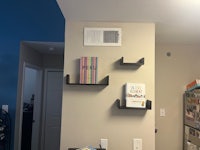 a room with a desk, bookshelves, and a fan