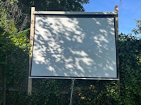 a large screen in a backyard with a tree in the background