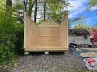 a wooden shed is being built in a backyard